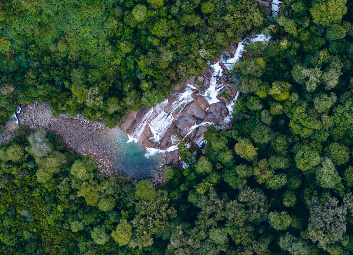 Aerial view of a waterfall surrounded by green trees. Aerial view of a waterfall surrounded by green trees.