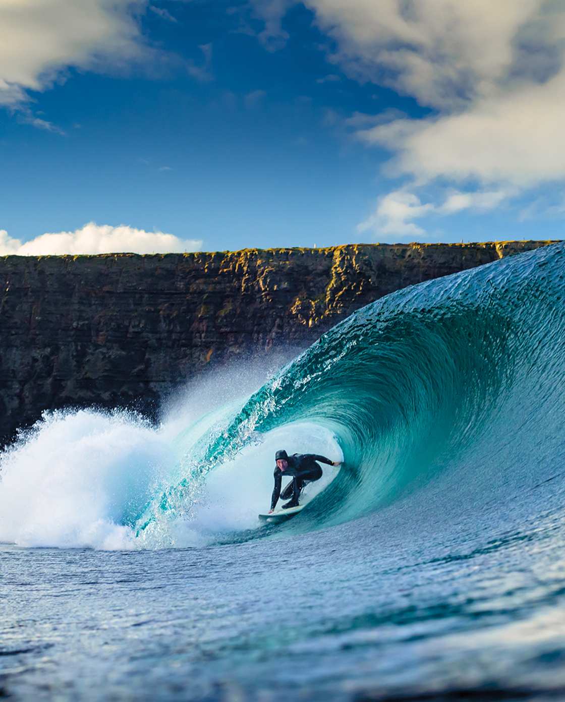 Man surfing through waves wearing a Patagonia Regulator wetsuit.