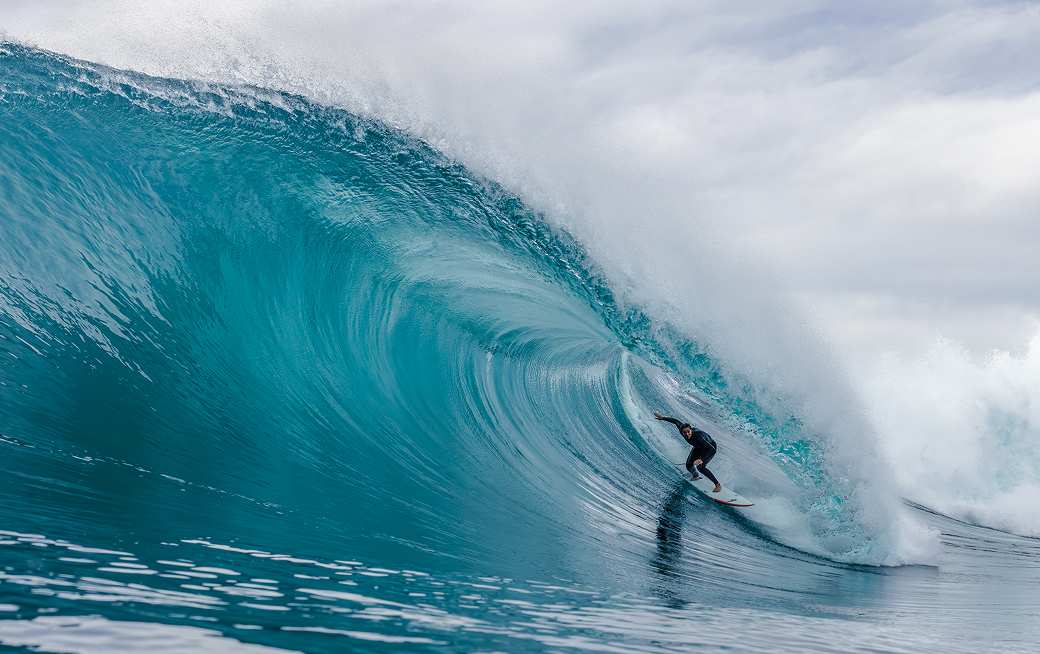 Surfer riding waves in a Patagonia Regulator® wetsuit.
