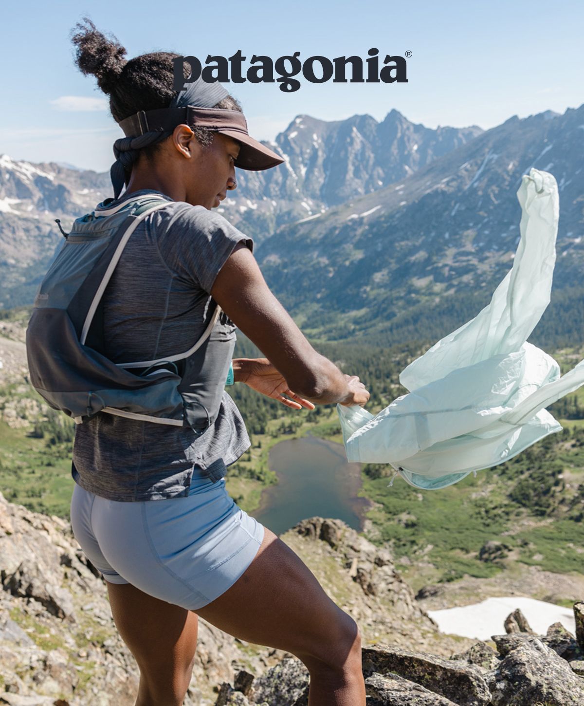 Patagonia® | Ambassador Peyton Thomas stands in the mountains with a jacket blowing in the wind.