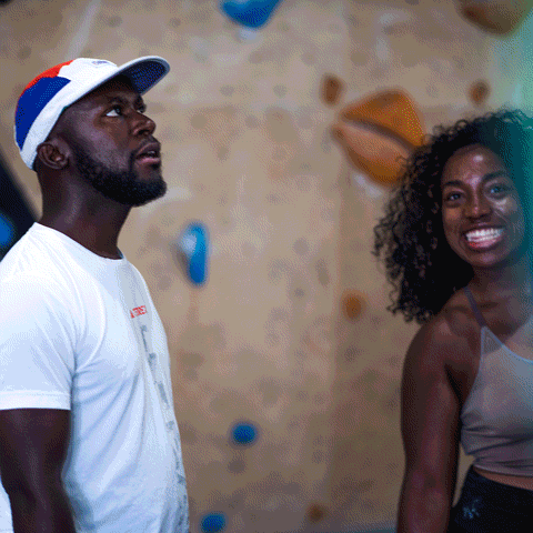 Two community members smiling together at an indoor climbing facility.